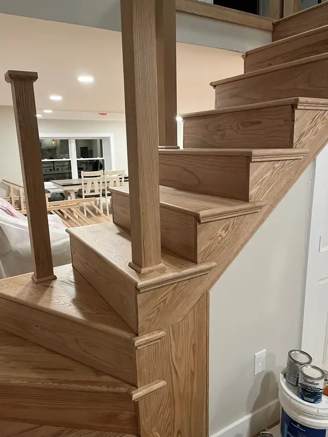 Custom-built wood staircase with winding treads and square newel posts in a renovated cottage