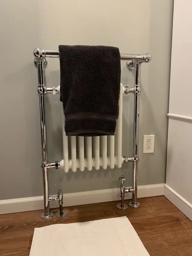 Chrome traditional heated towel radiator on a grey bathroom wall